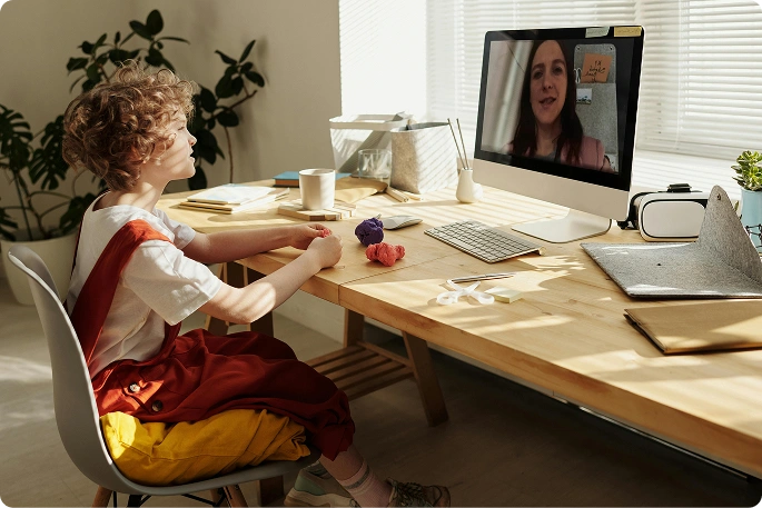 gyerek, aki asztali számítógépen vesz részt online órán, szimbolizálva a távoktatást, a videóórákat és a modern oktatást