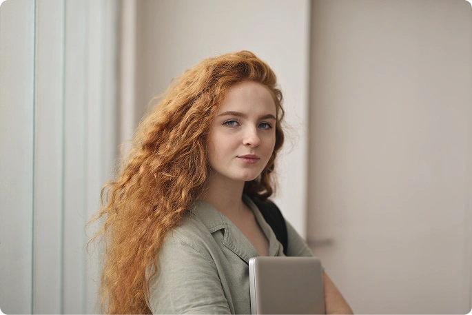 önbiztos fiatal nő laptopot tartva, aki az oktatást, a digitális készségeket és a modern hallgatói életmódot szimbolizálja