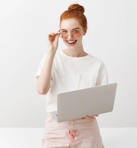 egy laptopot tartó, mosolygó fiatal nő, aki a távmunkát, az online tanulást és a modern digitális életmódot szimbolizálja